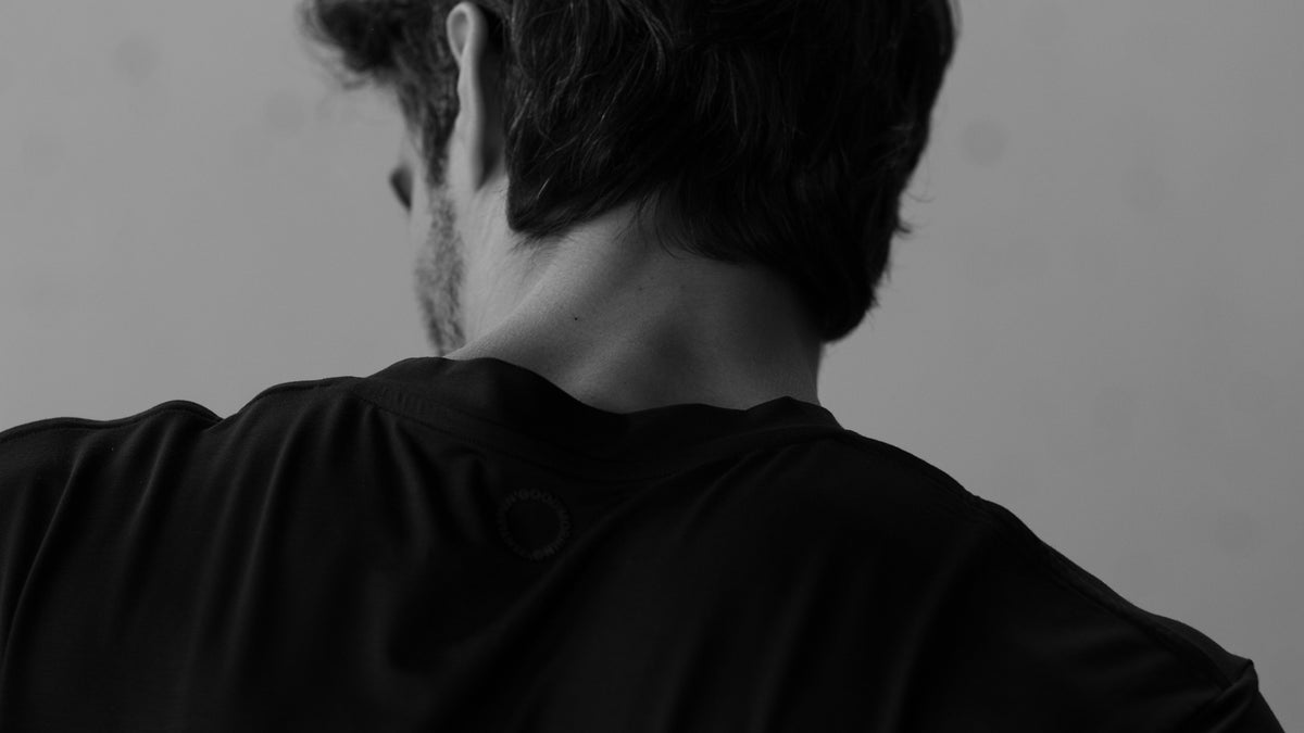 Rückenansicht eines Mannes im schwarzen SEACELL T-Shirt von Good Morning, Gentlemen! mit dezentem Logo im Nacken